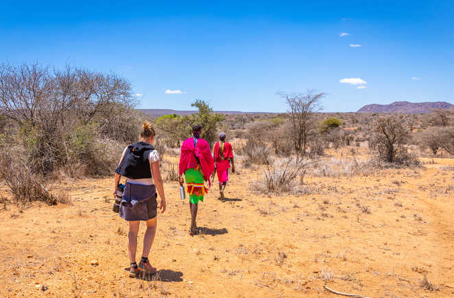 Randonneuse et masai marchant dans la savane au Kenya