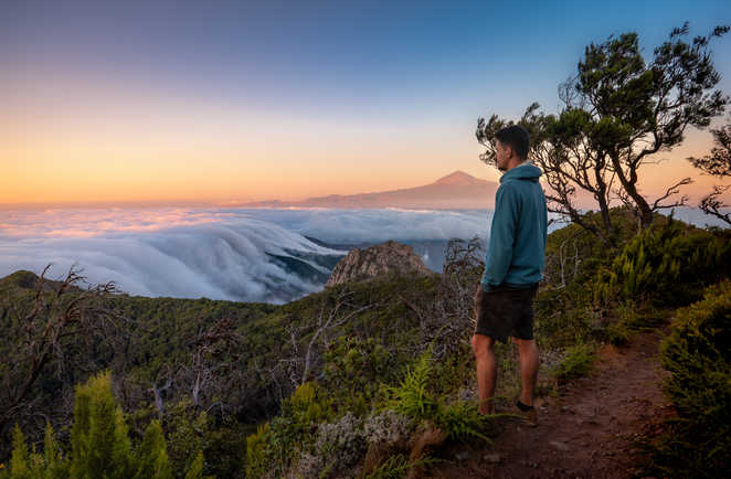 Une personne qui regarde le coucher de soleil depuis le Parc National de Garajonay avec le mont Teide en fond